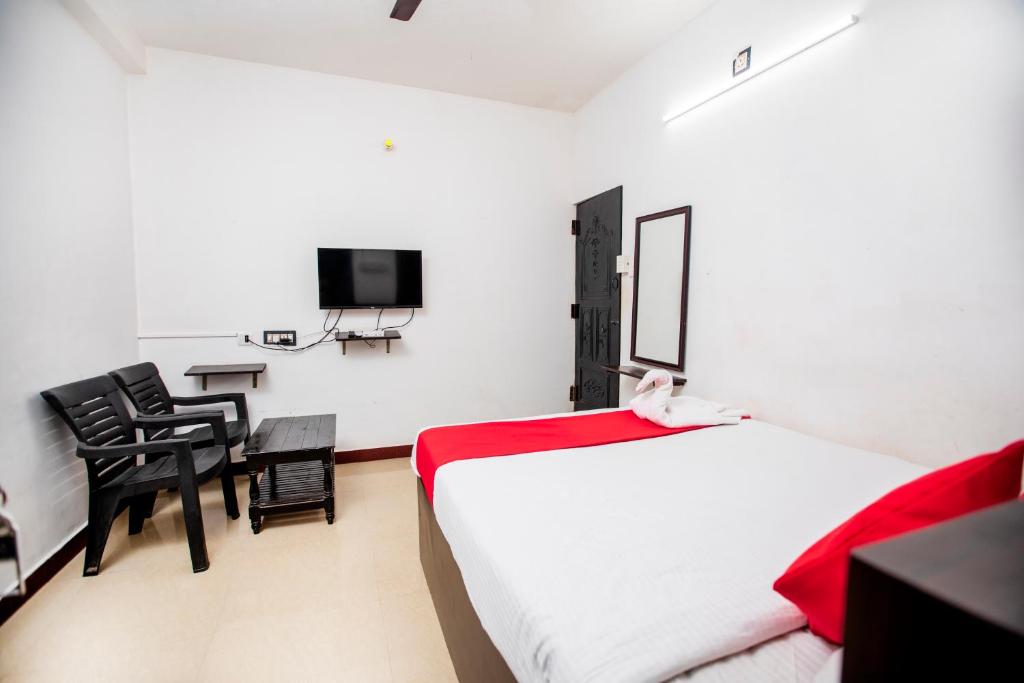 um quarto com uma cama, uma secretária e uma televisão em Hotel 1Square em Pondicherry