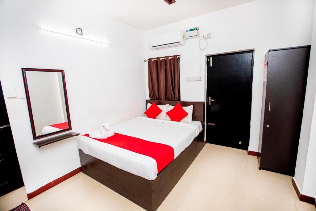 um quarto com uma cama com almofadas vermelhas e um espelho em Hotel 1Square em Pondicherry