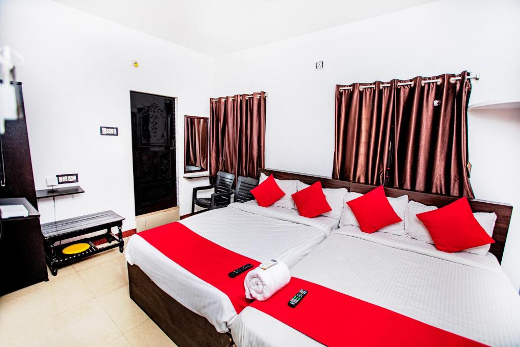 um quarto com uma cama grande e almofadas vermelhas em Hotel 1Square em Pondicherry