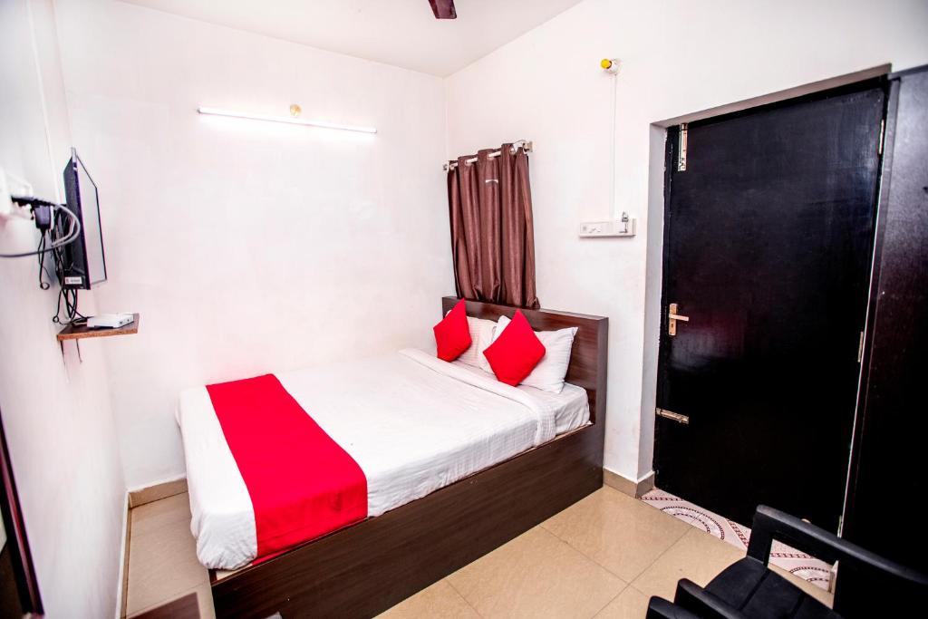 um pequeno quarto com uma cama com almofadas vermelhas em Hotel 1Square em Pondicherry