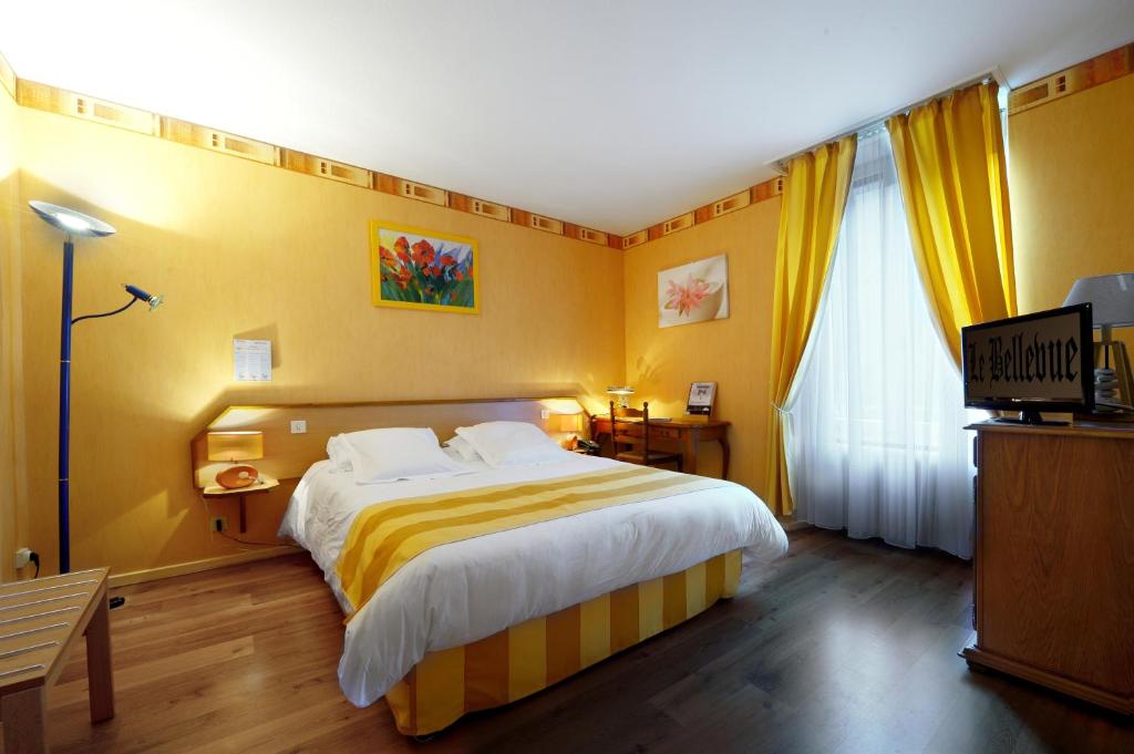 a bedroom with a large bed with yellow walls at Hotel Le Bellevue in Saint-Hippolyte