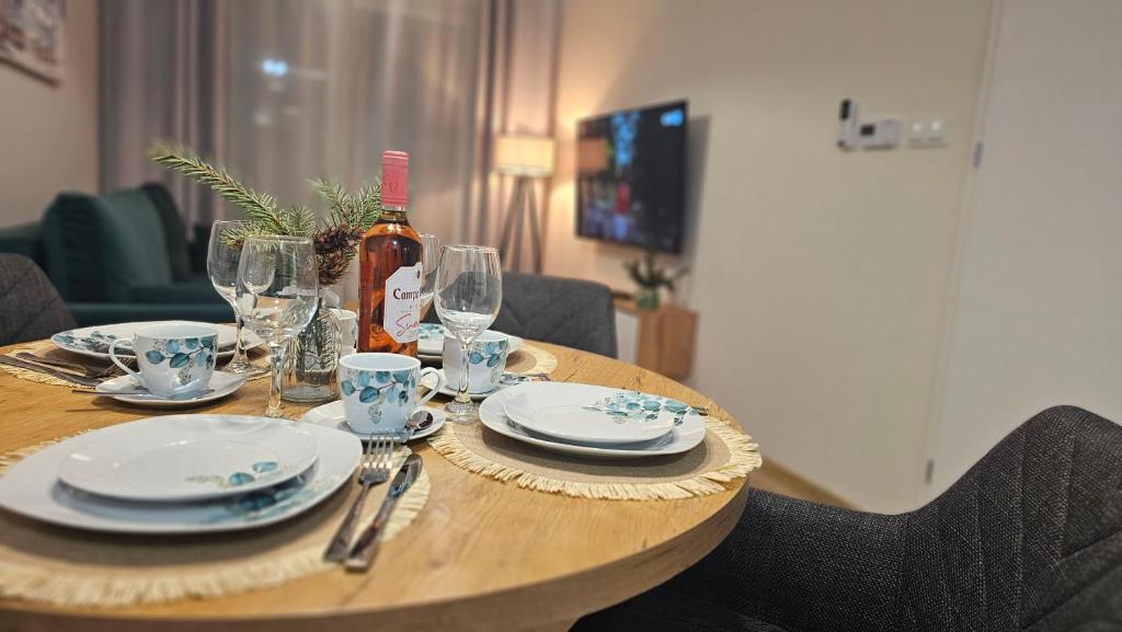a wooden table with a bottle of wine and glasses at Apartamenty Września IV in Września