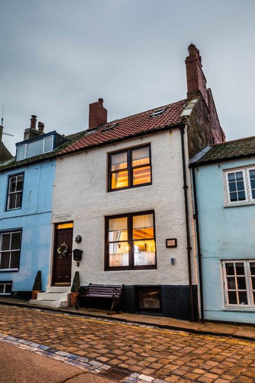 a white building with windows on a street at Captain Cook's Cottage, Staithes, North Yorkshire in Staithes