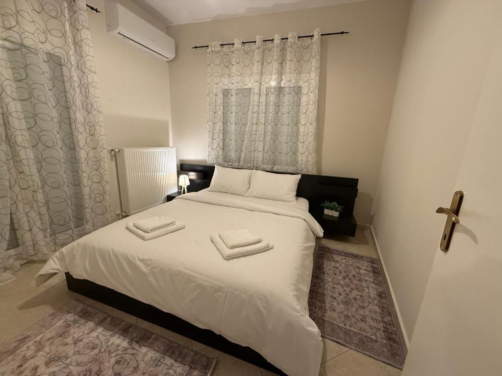 a bedroom with a bed with white sheets and a window at Ourania's Apartment Kastoria in Mavrokhórion