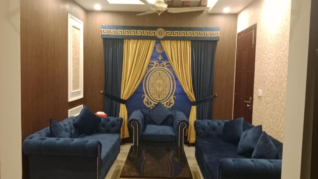ein Zimmer mit zwei blauen Sofas und einem Vorhang in der Unterkunft Hotel in Islamabad Luxurious 2 Bedroom in Islamabad