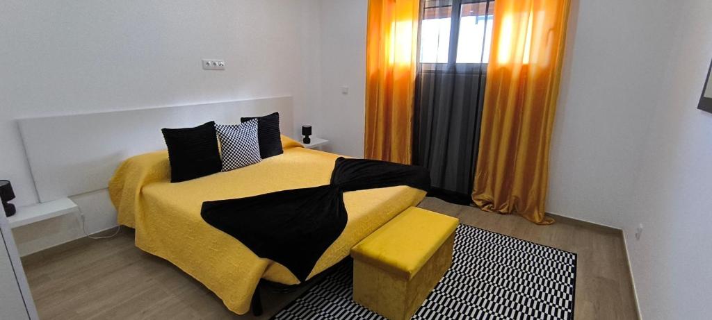 um quarto com uma cama amarela e preta e uma janela em O Infinito em Calhetas
