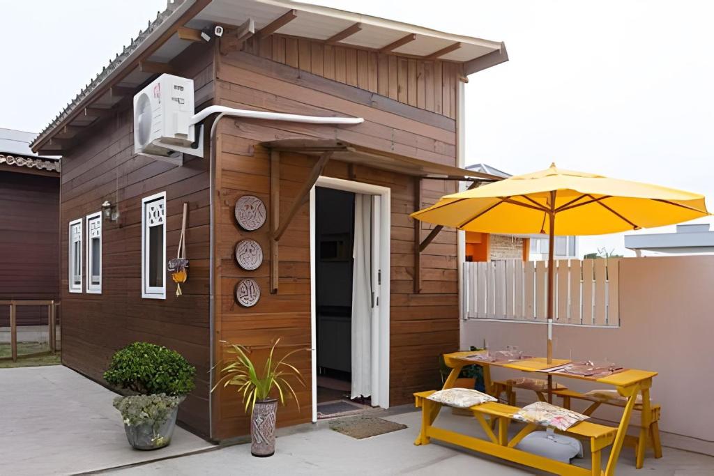 a small building with a table and an umbrella at Casa 2 quartos, 6 pessoas, perto da praia, ar condicionado, wi-fi, cozinha completa, lavanderia, in Florianópolis