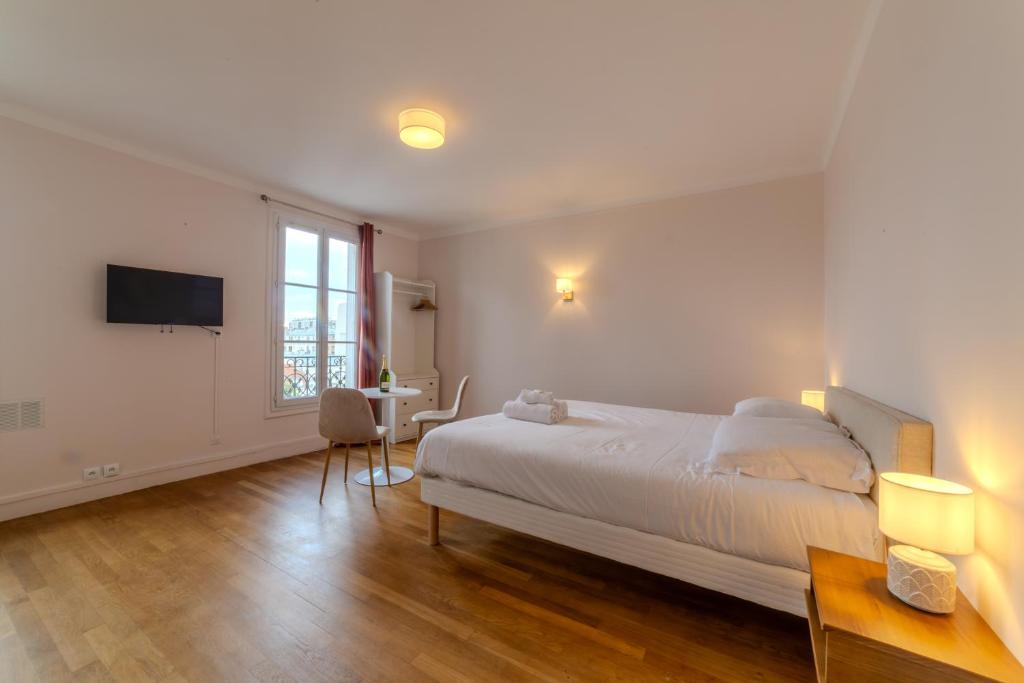 une chambre blanche avec un lit et une table dans l'établissement The charming Republic Place, à Paris