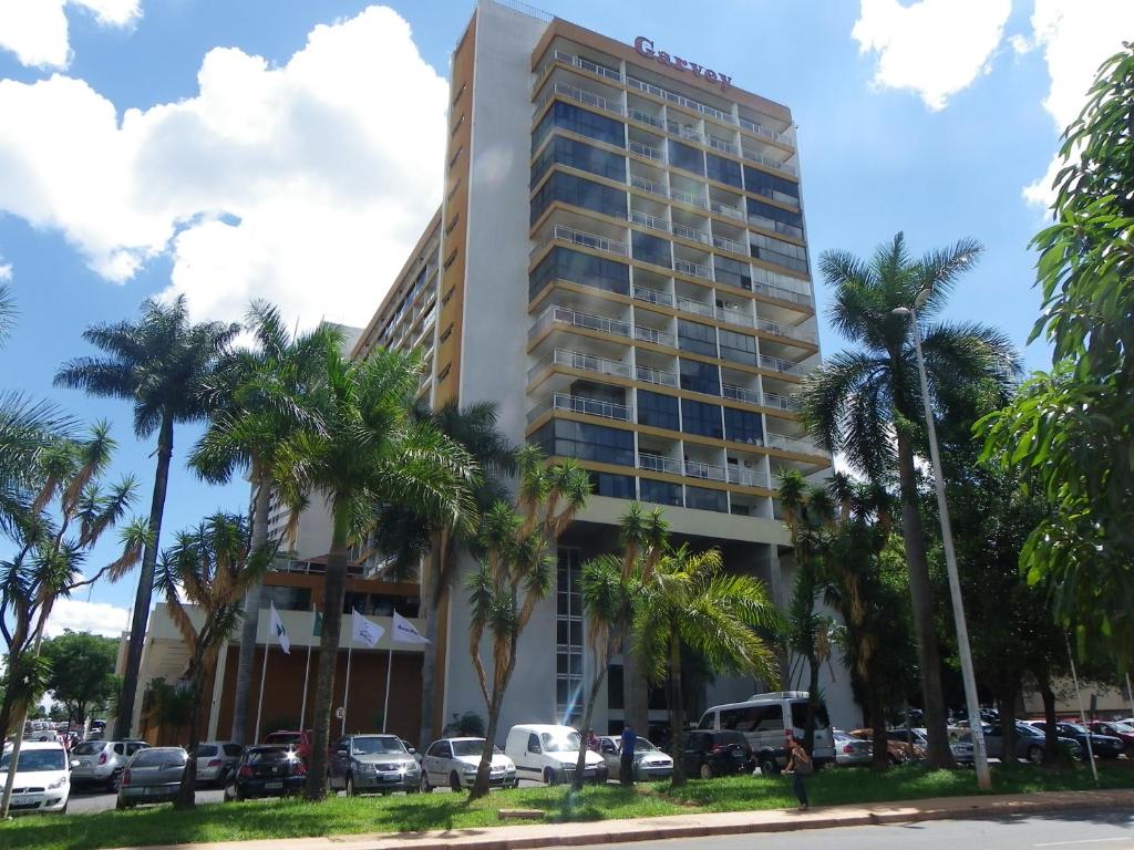 a tall building with palm trees in front of it at IKA Apart Hotel in Brasilia