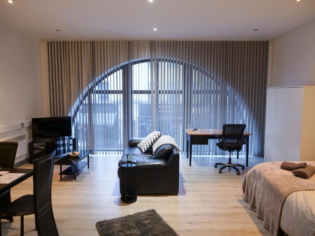 a bedroom with a bed and a couch and a desk at Spacious and Modern Studio Apartment Swansea City Centre in Swansea