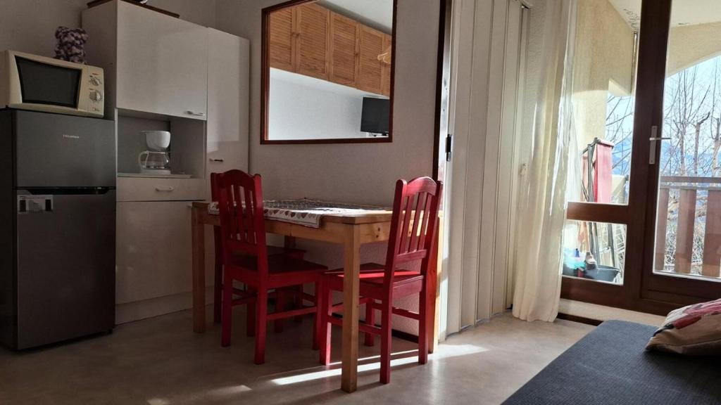 une cuisine avec une table et quatre chaises rouges dans l'établissement Résidence Vue Et Soleil - APPARTEMENT ALPE DHUEZ QUARTIER PASSEAUX MAE-3961, à Huez