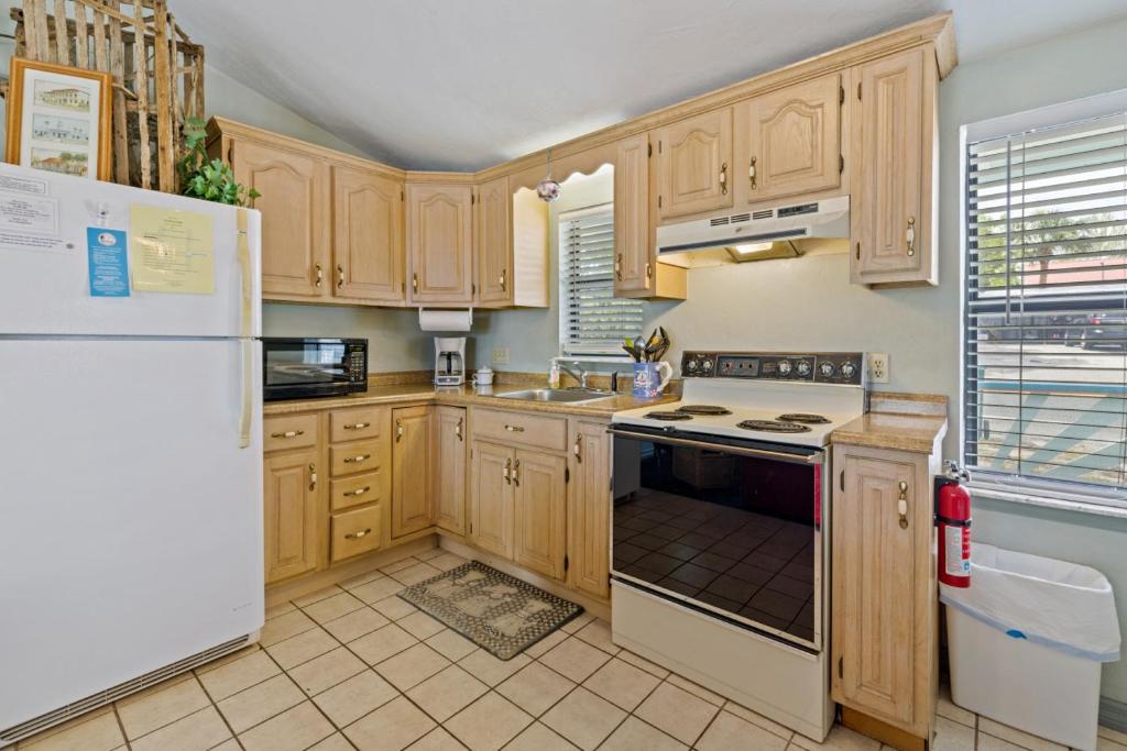 Una cocina con gabinetes de madera y un refrigerador blanco. en Rains Waterfront Cottage, en Cedar Key