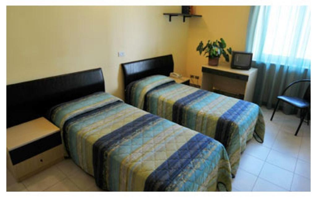 Habitación de hotel con 2 camas y escritorio en Hotel Stella Bianca, en Scarmagno