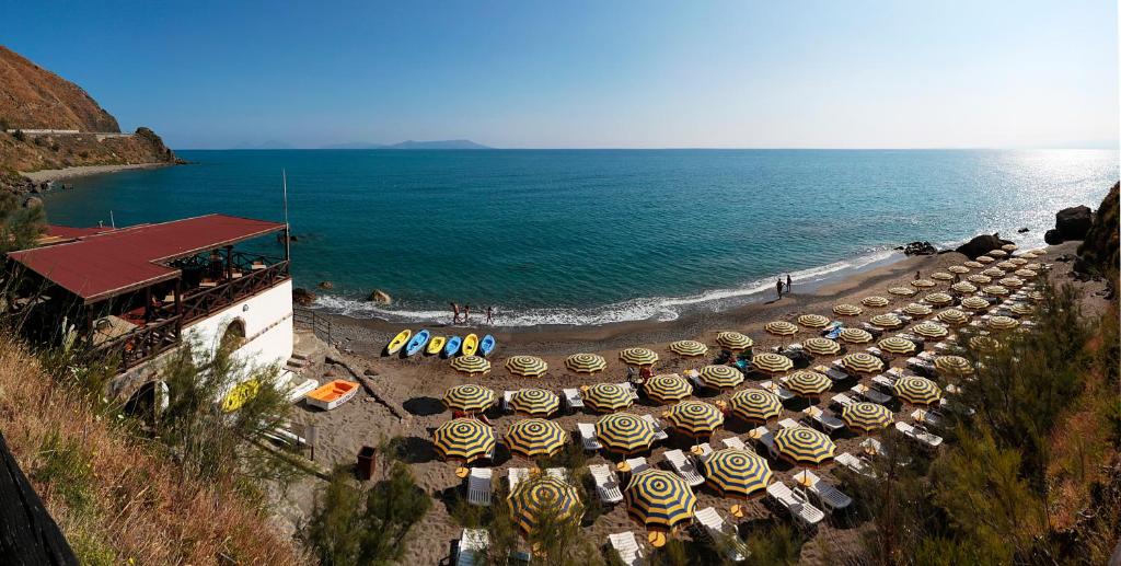 a row of umbrellas on a beach next to the ocean at VRclub - Villa Ridente Residence in Gioiosa Marea
