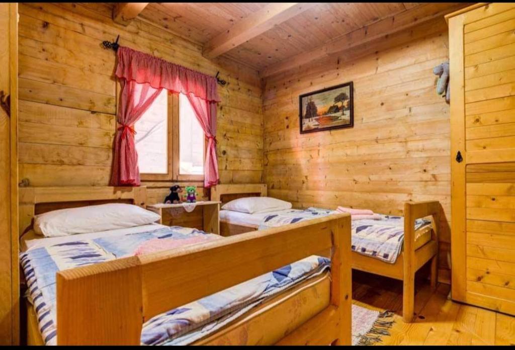 a bedroom with two beds in a log cabin at Eko apartments Drvljanik in Kaluđerac