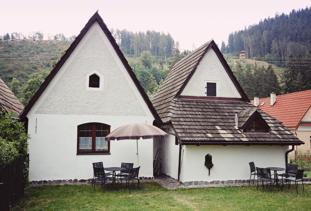Casa blanca con mesas, sillas y sombrilla en Syparne, en Liptovský Ján