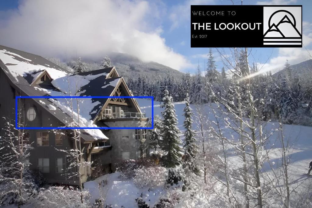 una casa cubierta de nieve con una montaña en el fondo en THE LOOKOUT PENTHOUSE &#47;&#47; a luxe suite in Whistler, en Whistler