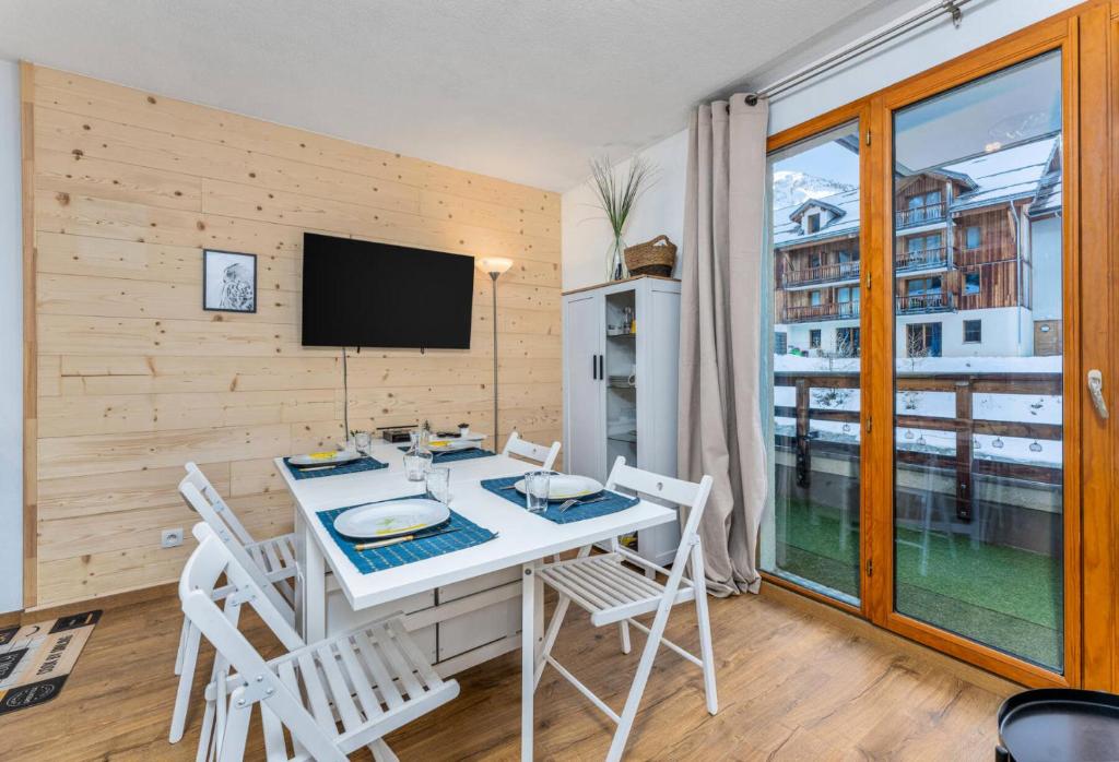 une salle à manger avec une table, des chaises et une télévision dans l'établissement Résidence Les Terrasses Du Soleil D'or - Chaleureux appartement aux portes des pistes MAE-6544, aux Orres