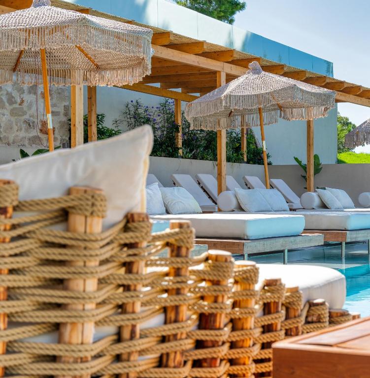 a bunch of wicker chairs and umbrellas next to a pool at Myzith Luxury Suites in Keri