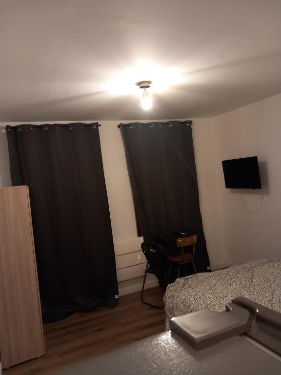 ein Schlafzimmer mit schwarzen Vorhängen und einem Bett und einem Fernseher in der Unterkunft Hébergement Cozy à Deville-lès-Rouen - 13 min Rouen in Déville-lès-Rouen