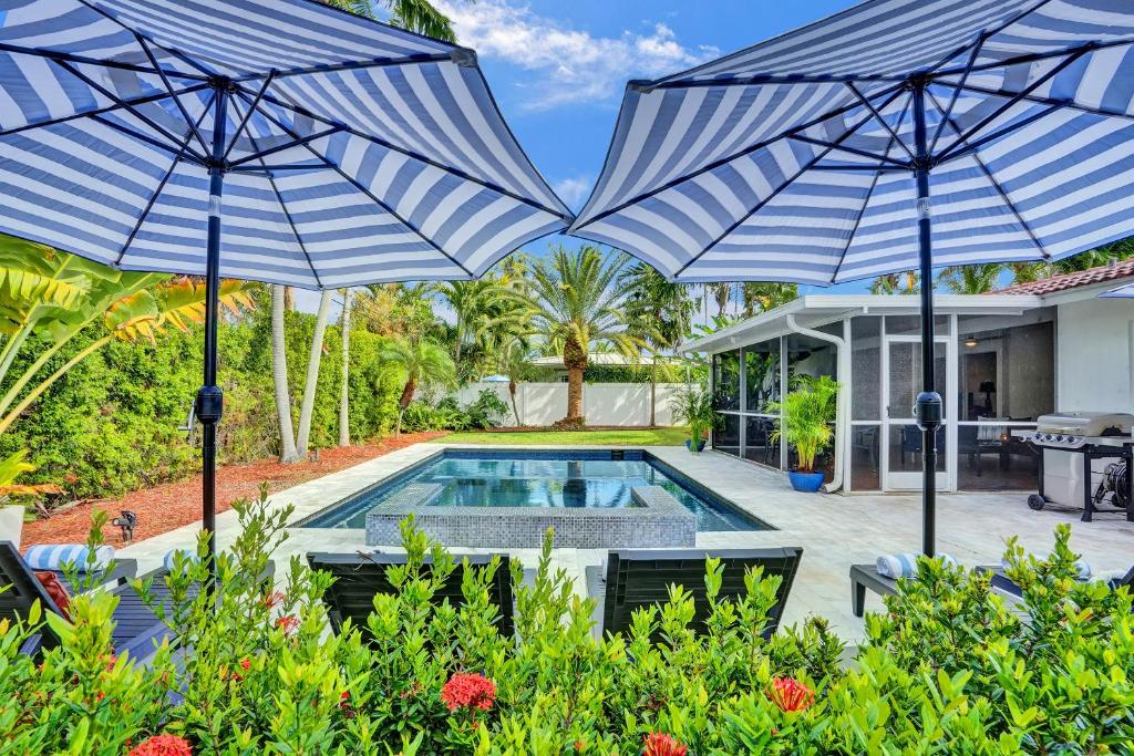 ein Haus mit einem Pool und zwei Sonnenschirmen in der Unterkunft Coconut Clubhouse - Heated Pool - Hot tub - Ping Pong in Fort Lauderdale