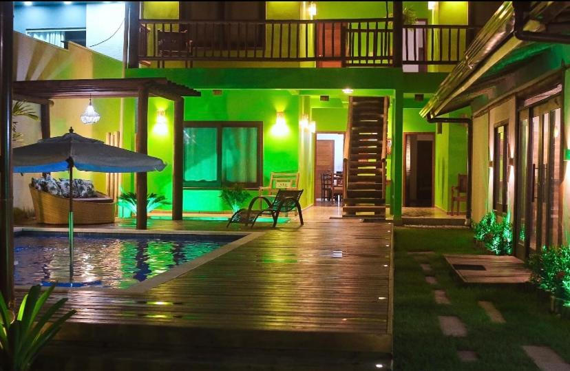 a house with a swimming pool and an umbrella at Village da Mata Arraial in Porto Seguro