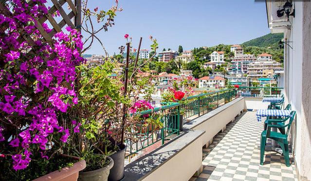 a balcony with purple flowers and a view of a city at Attic Apartment in Rapallo