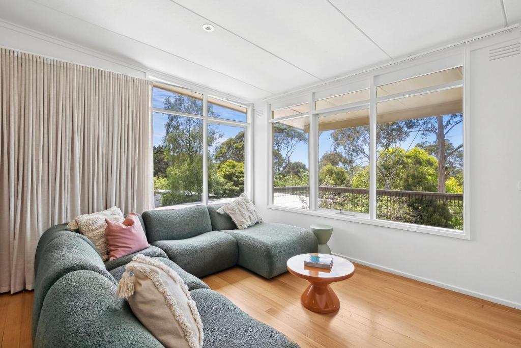 a living room with a couch and large windows at Prasino in Lorne