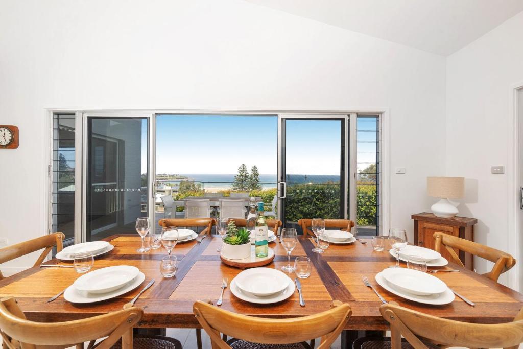 a large wooden table with chairs and a large window at Riverleigh, Gerroa in Gerroa