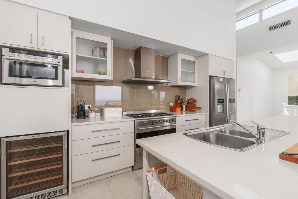 a kitchen with white cabinets and stainless steel appliances at Riverleigh, Gerroa in Gerroa