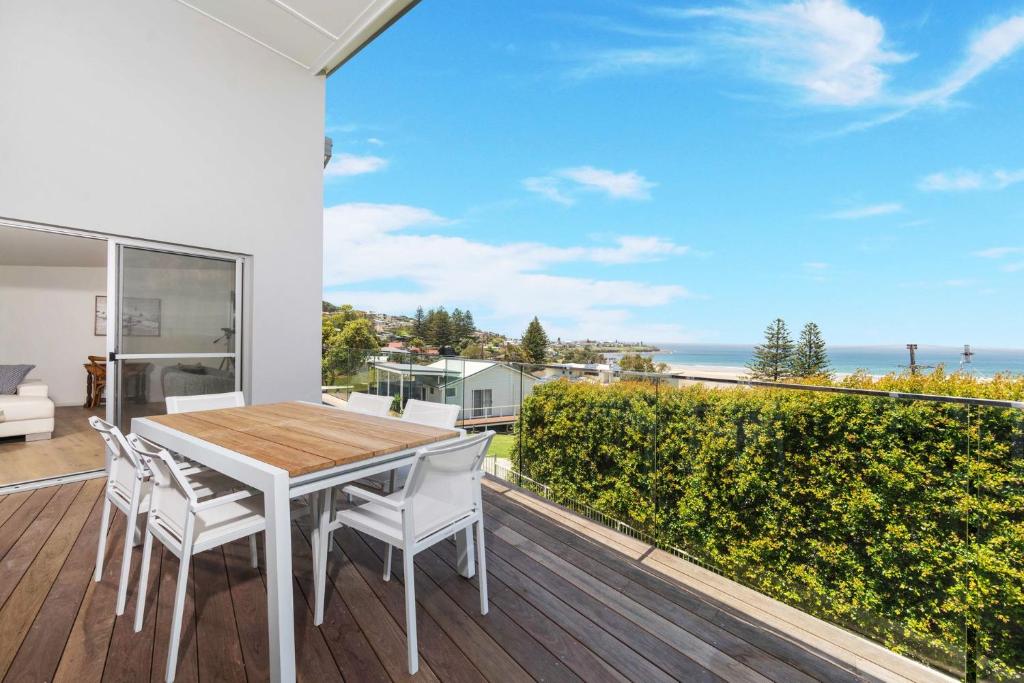 a dining room with a table and chairs on a balcony at Riverleigh, Gerroa in Gerroa
