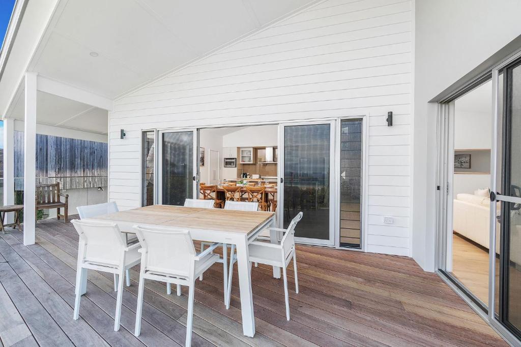 a dining room with a table and white chairs at Riverleigh, Gerroa in Gerroa