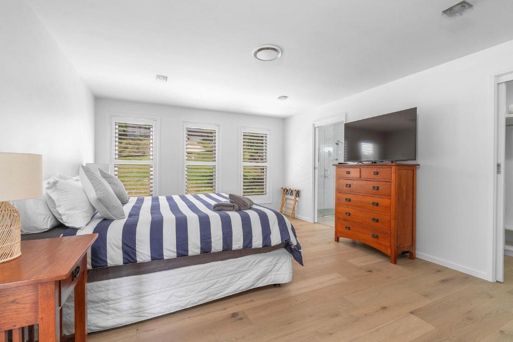 a bedroom with a bed and a dresser and a television at Riverleigh, Gerroa in Gerroa