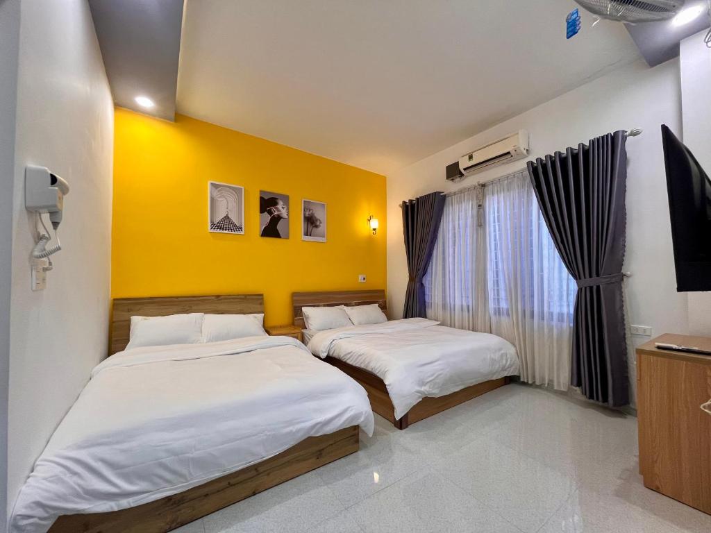 two beds in a room with a yellow wall at 1979 Homestay 2 in Hue