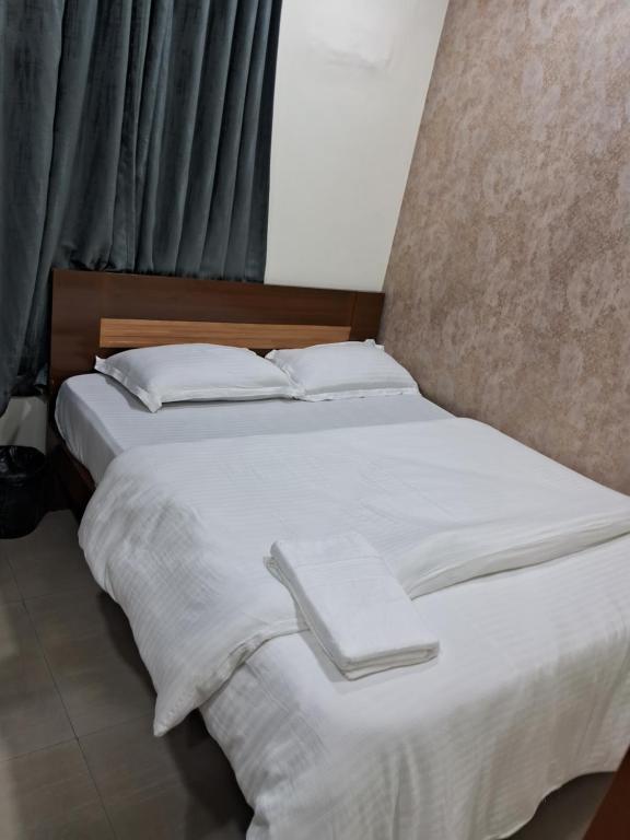 a bed with white sheets and pillows and a window at Hotel Oasisinn in Hyderabad