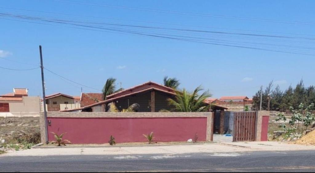 a house with a pink wall next to a street at Casa de praia in Luis Correia