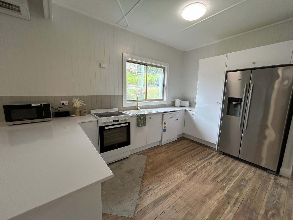 a kitchen with a refrigerator and a counter top at Coastal Echo - Oceanstays - Pet Friendly in Yamba
