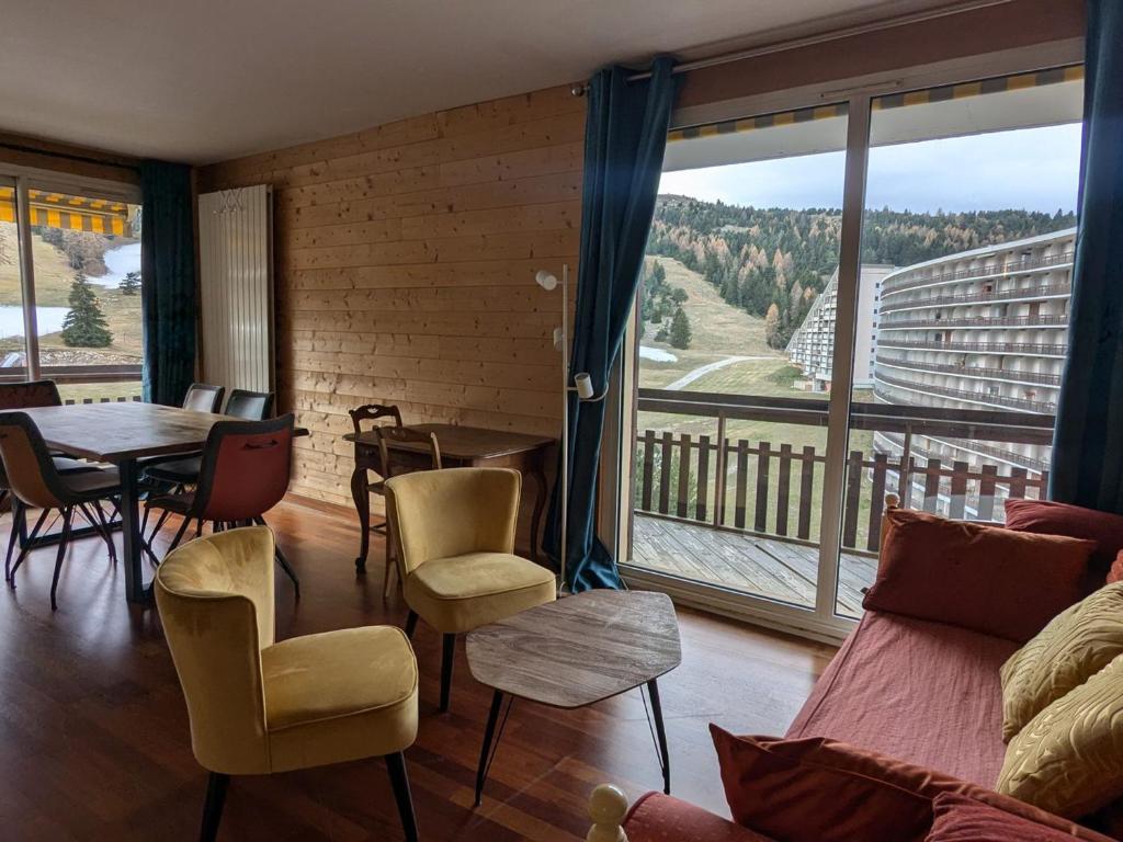 - un salon avec une table, des chaises et une grande fenêtre dans l'établissement Appartement 8 pers, 3 pièces, sud-ouest, parking et animaux admis - FR-1-504-690, à Superdevoluy