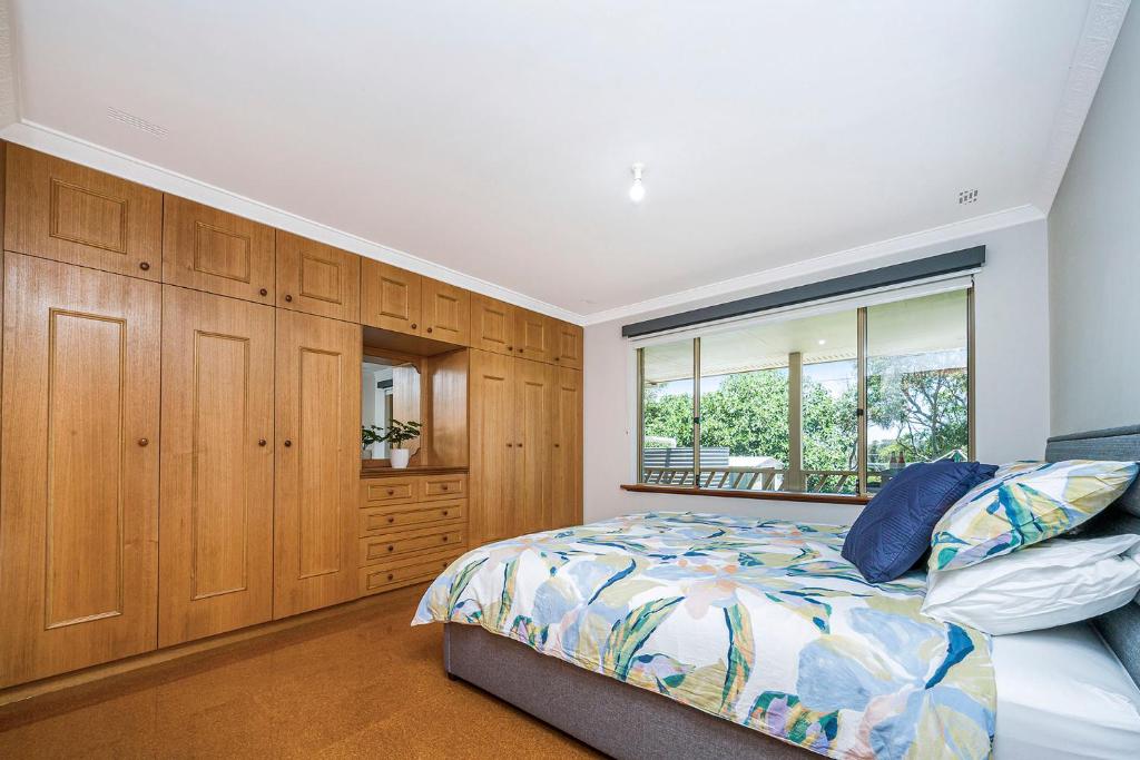 a bedroom with a bed and wooden cabinets and a window at Moore than a Shack in Guilderton