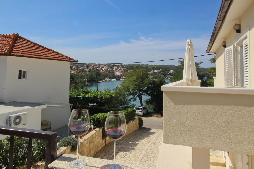 two glasses of wine sitting on the balcony of a house at Apartments Scheich in Šilo