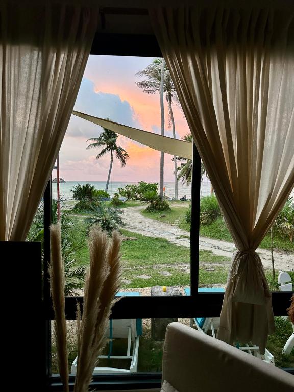 a room with a view of the beach from a window at 2BD beachfront house in Chaloclum in Mae Haad