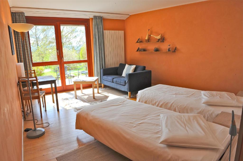 a bedroom with two beds and a couch and a chair at EcoHotel L’Aubier in Montézillon