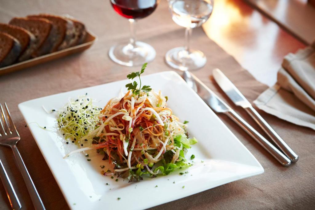 a plate of food on a table with wine glasses at EcoHotel L’Aubier in Montézillon