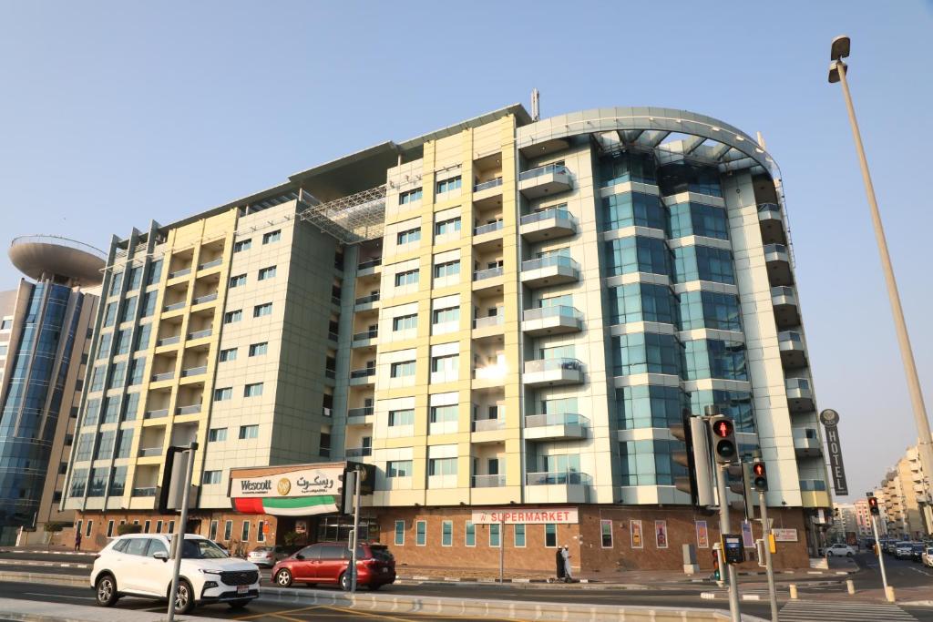 un grand bâtiment avec des voitures garées devant dans l'établissement Wescott Plaza Hotel Apartments LLC Formerly West Zone Plaza Hotel Apts, à Dubaï