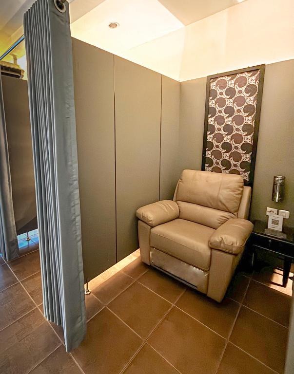 a reclining chair in a corner of a room at d'primahotel Airport Jakarta Terminal 1A in Tangerang