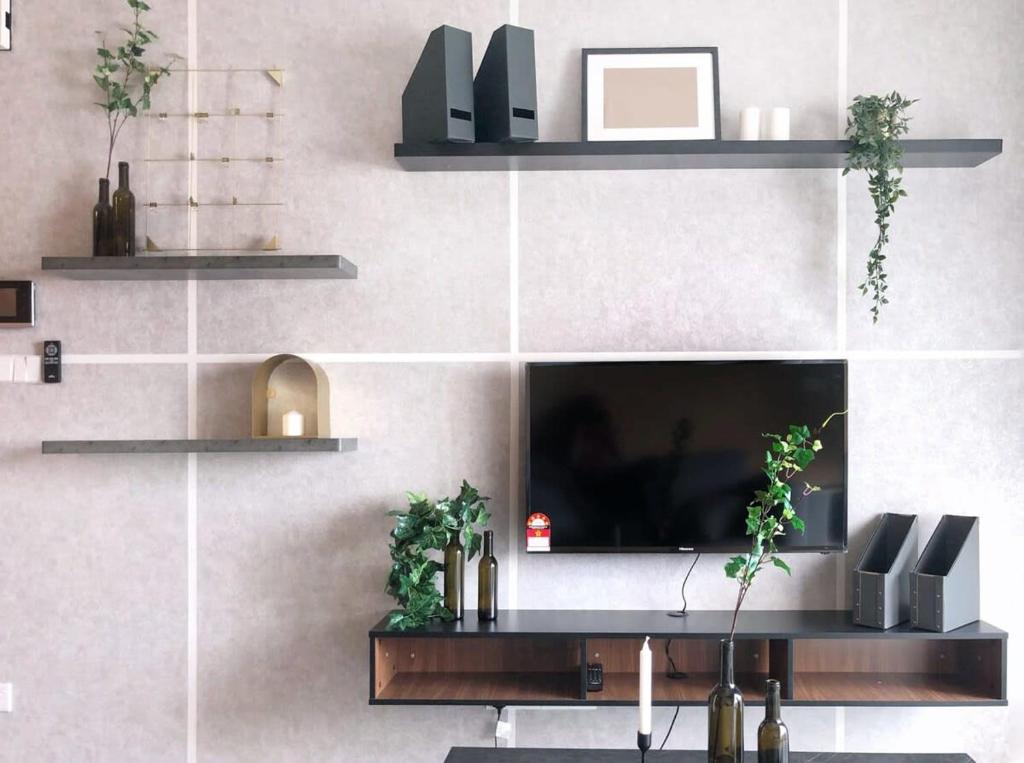 Stylish & Cozy Stay at Suasana Suites JB 11 في جوهور باهرو: غرفة معيشة مع تلفزيون على جدار مع رفوف