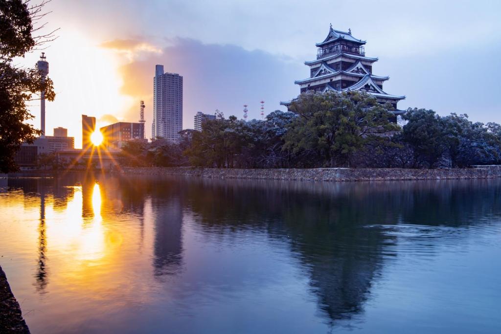 a sunset over a lake with a tower in the background at Rihga Royal Hotel Hiroshima in Hiroshima