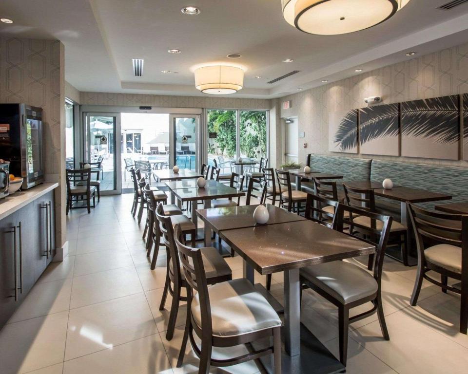 a restaurant with wooden tables and chairs and windows at Comfort Suites Miami Airport North in Miami