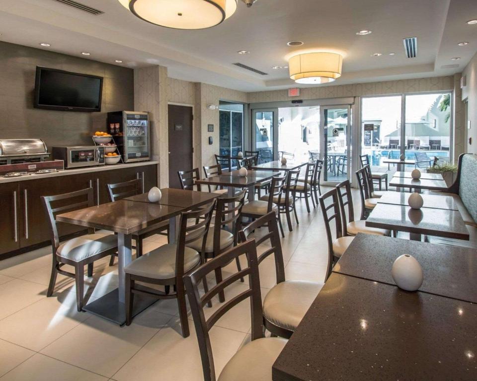 a restaurant with tables and chairs and a kitchen at Comfort Suites Miami Airport North in Miami