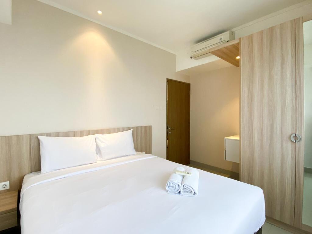 a bedroom with a large white bed with two towels on it at Cozy and Minimalist 2BR at 8th Floor The Oasis Cikarang Apartment By Travelio in Cikarang